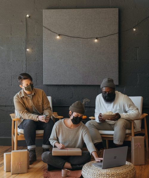 SME Outsorcerer Three coworkers wearing masks on a Surface laptop with Christmas presents on a cart